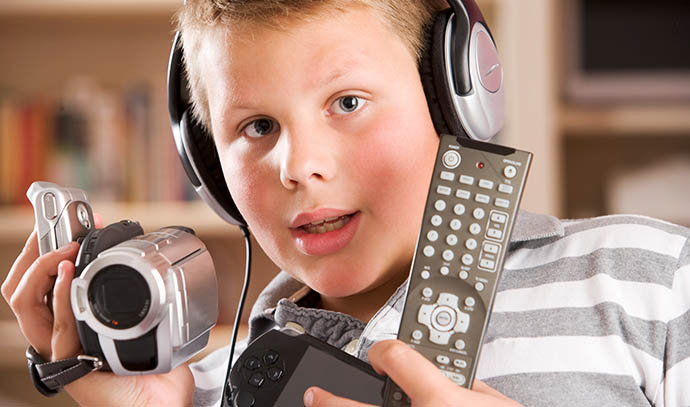 young-boy-wearing-headphones-bedroom-holding-many-electronic-devices